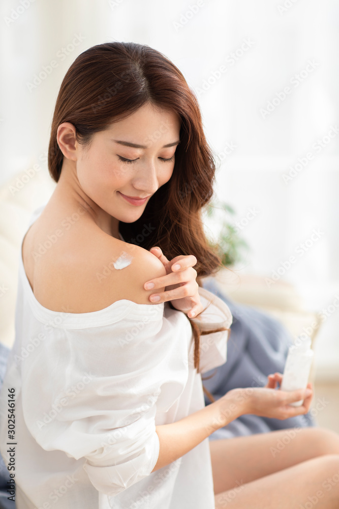 Young Chinese woman applying moisturizer at home Young Chinese woman applying moisturizer at home