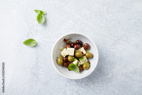 Green and Kalamata Olives, Capers and Feta Cheese on Bright Stone Background. Healthy Snack Idea. Top view. Copy space. 
