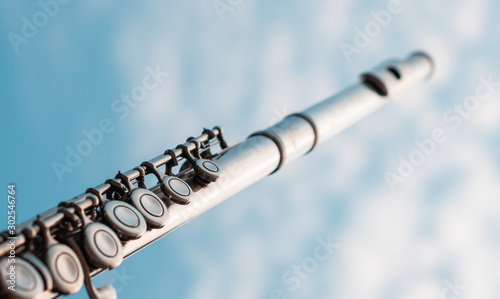 Valokuva Detail of silver flute key shining by sunset light with cloudy blue sky backgrou