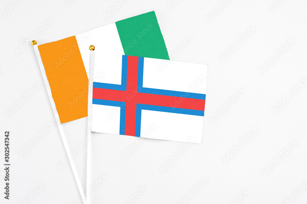 Faroe Islands and Cote D'Ivoire stick flags on white background. High quality fabric, miniature national flag. Peaceful global concept.White floor for copy space. Faroe Islands and Cote D'Ivoire stick flags on white background. High quality fabric, miniature national flag. Peaceful global concept.White floor for copy space.