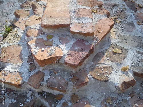 The restored wall of the building of Roman times. Sunlight accentuates the warm brown-red shades of uneven bricks. Archaeological excavations of steps and walls of ancient buildings photo