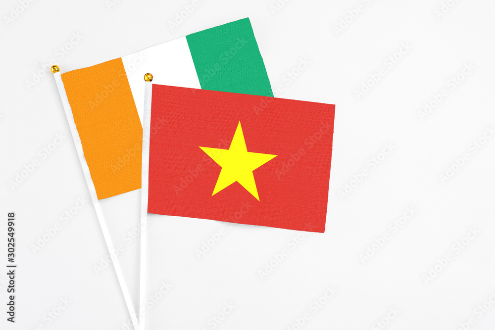 Vietnam and Cote D'Ivoire stick flags on white background. High quality fabric, miniature national flag. Peaceful global concept.White floor for copy space. Vietnam and Cote D'Ivoire stick flags on white background. High quality fabric, miniature national flag. Peaceful global concept.White floor for copy space.