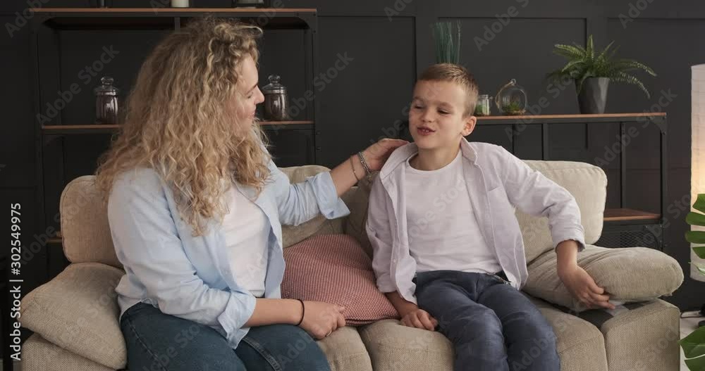 Happy mother and son talking on sofa at home