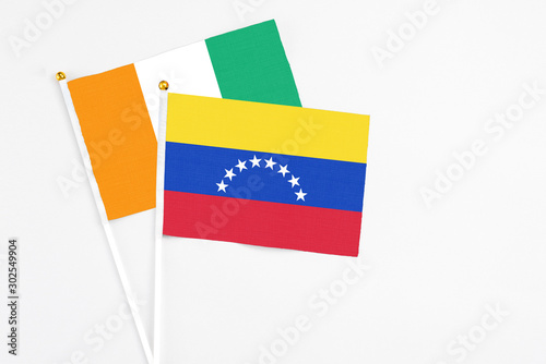 Venezuela and Cote D Ivoire stick flags on white background. High quality fabric  miniature national flag. Peaceful global concept.White floor for copy space.