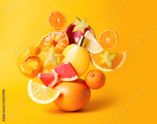 Perfume bottle with refreshing fruity smell between fresh fruits on yellow background