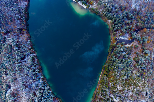 aerial view to blue lake Alatsee with snowy forest trees at winter photo