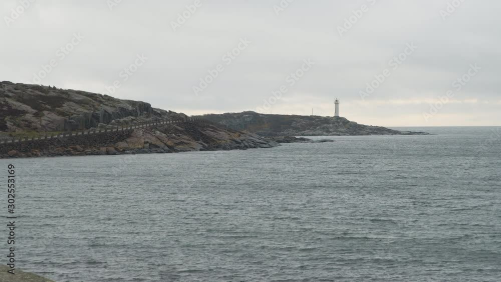 A rocky coastline with a lighthouse on a peninsula. A rocky coastline with a lighthouse on a peninsula.