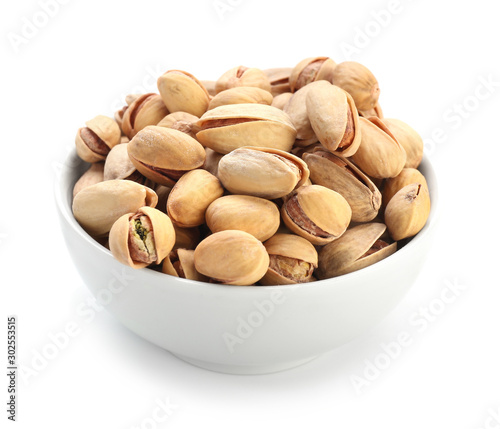 Bowl with tasty pistachio nuts isolated on white