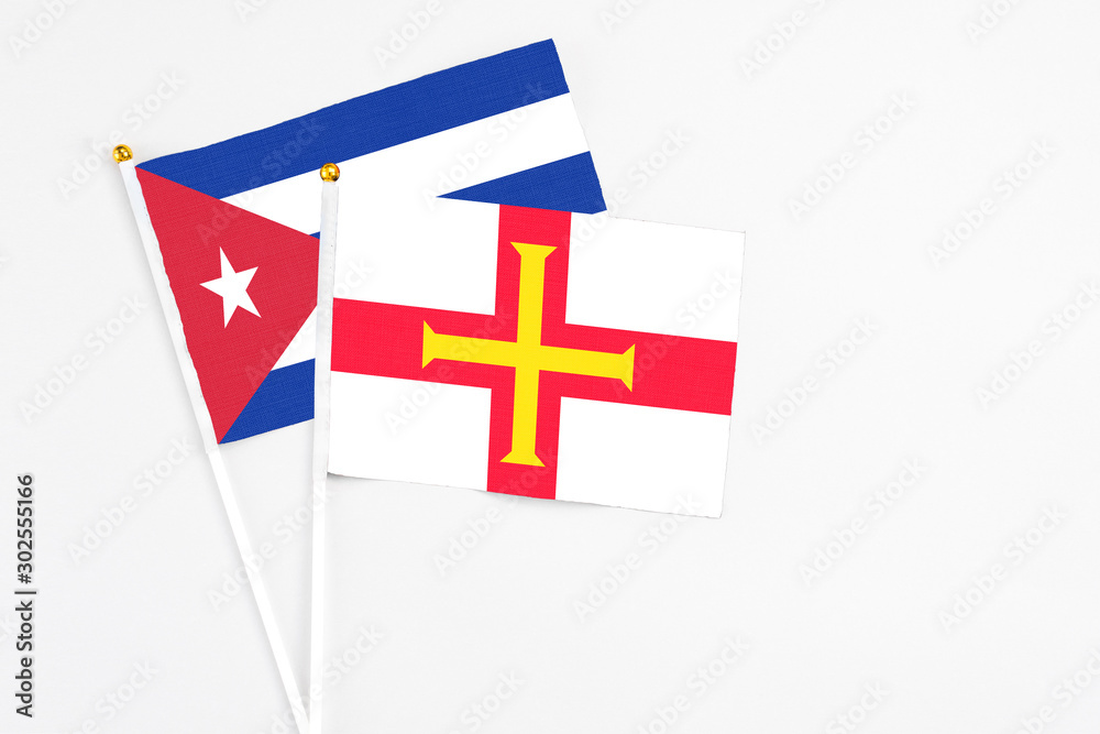 Guernsey and Cuba stick flags on white background. High quality fabric, miniature national flag. Peaceful global concept.White floor for copy space.