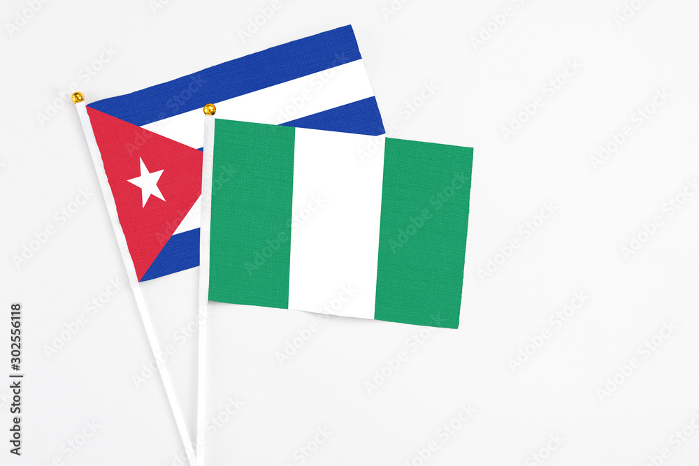 Nigeria and Cuba stick flags on white background. High quality fabric, miniature national flag. Peaceful global concept.White floor for copy space. Nigeria and Cuba stick flags on white background. High quality fabric, miniature national flag. Peaceful global concept.White floor for copy space.