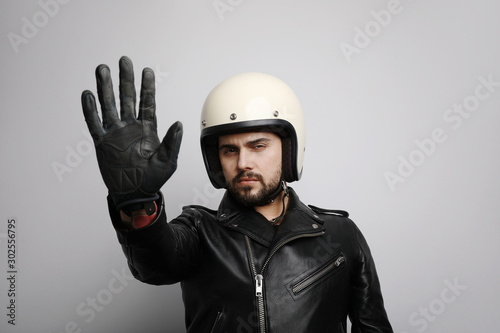Close-up portrait of biker with white helmet making stop signs with his hand. Isolated.