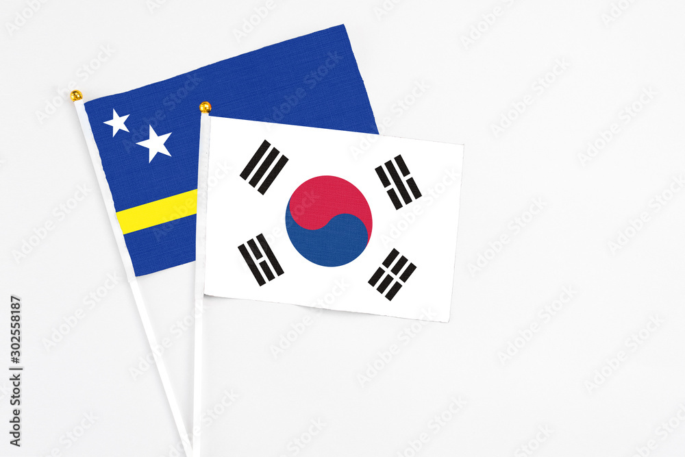 South Korea and Curacao stick flags on white background. High quality fabric, miniature national flag. Peaceful global concept.White floor for copy space.