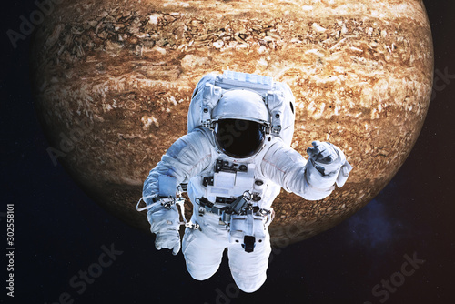 Fototapeta Naklejka Na Ścianę i Meble -  Astronaut close to the fantastic far brown rock planet. Science fiction. Elements of the image are furnished by NASA