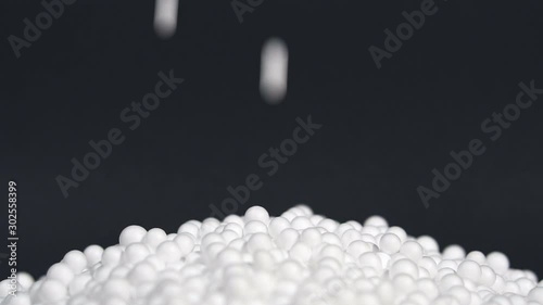 White round polystyrene packaging material drop from injection machine in slow motion, modern foam bead ball decoration cause global warming from chemical waste photo