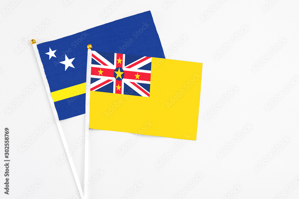 Niue and Curacao stick flags on white background. High quality fabric, miniature national flag. Peaceful global concept.White floor for copy space. Niue and Curacao stick flags on white background. High quality fabric, miniature national flag. Peaceful global concept.White floor for copy space.