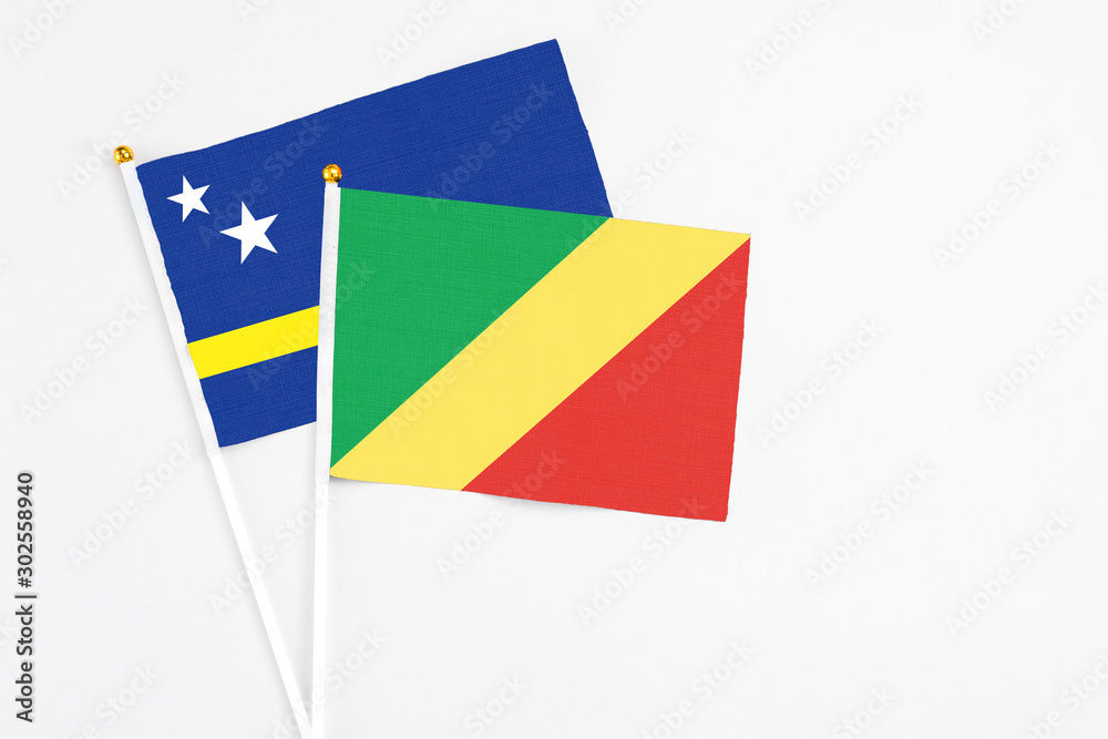 Fototapeta premium Republic Of The Congo and Curacao stick flags on white background. High quality fabric, miniature national flag. Peaceful global concept.White floor for copy space.