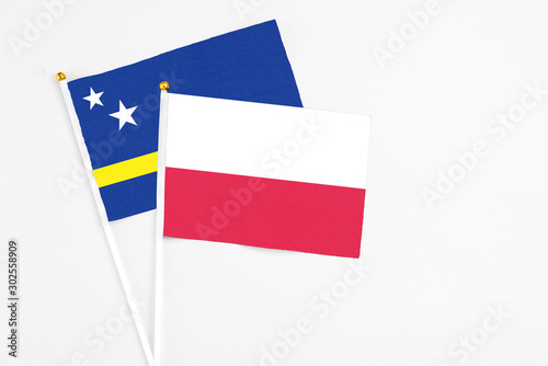 Poland and Curacao stick flags on white background. High quality fabric  miniature national flag. Peaceful global concept.White floor for copy space.