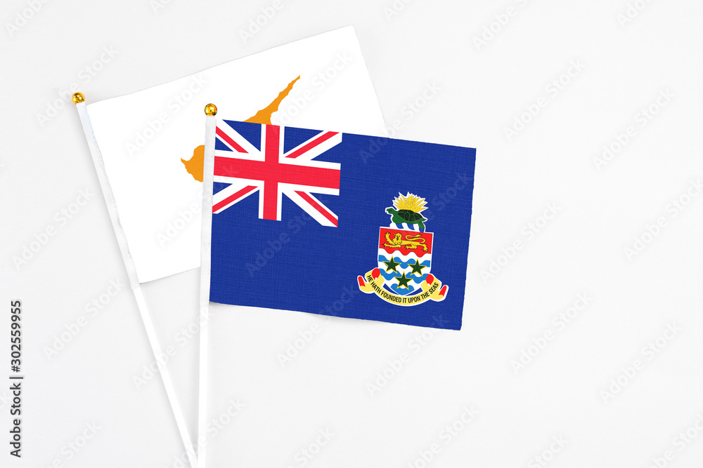 Fototapeta premium Cayman Islands and Cyprus stick flags on white background. High quality fabric, miniature national flag. Peaceful global concept.White floor for copy space.