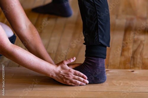 Closeup view photo of a person changing and stabilizing the position of a persons foot while standing on a wooden floor