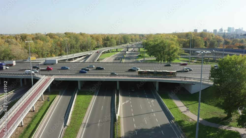 Drone shot from a slow-moving freeway in the afternoon, showing cars and light lanes. Warsaw, Poland. Drone shot at a highway with a clover junction with bridges and ramps, heavy traffic. Drone shot from a slow-moving freeway in the afternoon, showing cars and light lanes. Warsaw, Poland. Drone shot at a highway with a clover junction with bridges and ramps, heavy traffic.