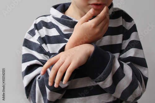 boy, a child in a striped jumper holds on to the lower jaw, the second hand hung limp from suffering, toothache concept