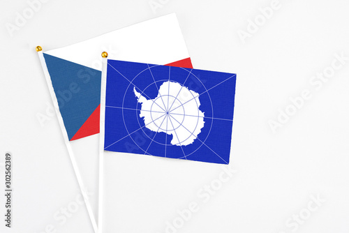 Antarctica and Cyprus stick flags on white background. High quality fabric, miniature national flag. Peaceful global concept.White floor for copy space.