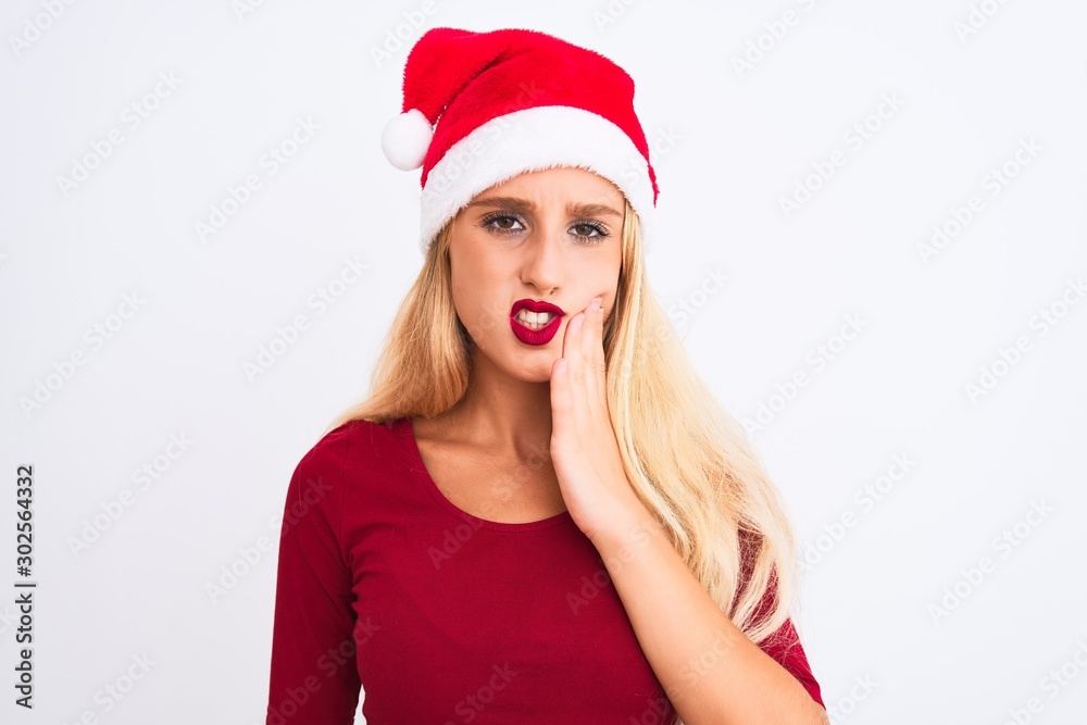 Young beautiful woman wearing Christmas Santa hat over isolated white background touching mouth with hand with painful expression because of toothache or dental illness on teeth. Dentist concept. Young beautiful woman wearing Christmas Santa hat over isolated white background touching mouth with hand with painful expression because of toothache or dental illness on teeth. Dentist concept.