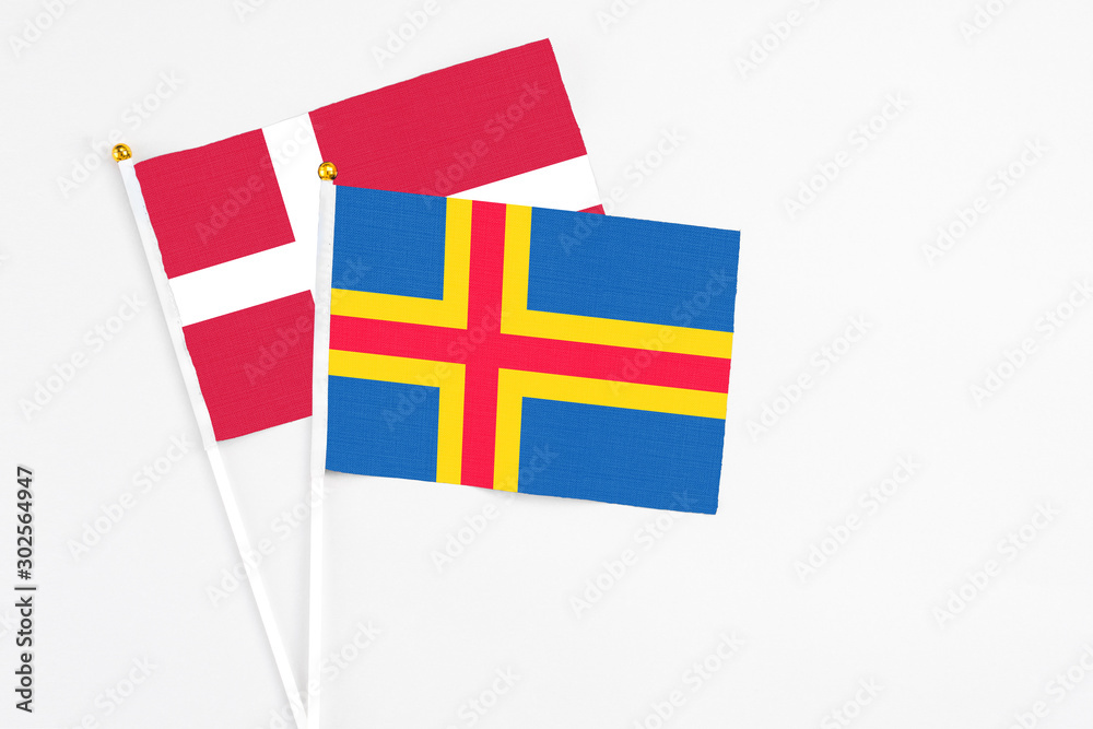 Aland Islands and Denmark stick flags on white background. High quality fabric, miniature national flag. Peaceful global concept.White floor for copy space.