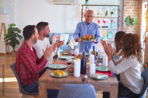 Beautiful family smiling happy and confident. Showing roasted turkey and applauding celebrating Christmas at home