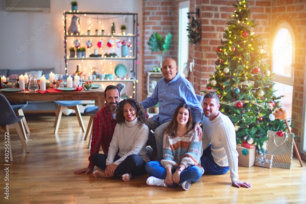 Beautiful family smiling happy and confident. Sitting on the floor and posing with tree celebrating Christmas at home