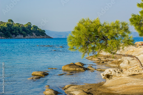 beautiful peaceful summer vacation destination place far from civilization  rocky island shore line with vivid green tropic tree branches above lagoon smooth blue water surface © Артём Князь