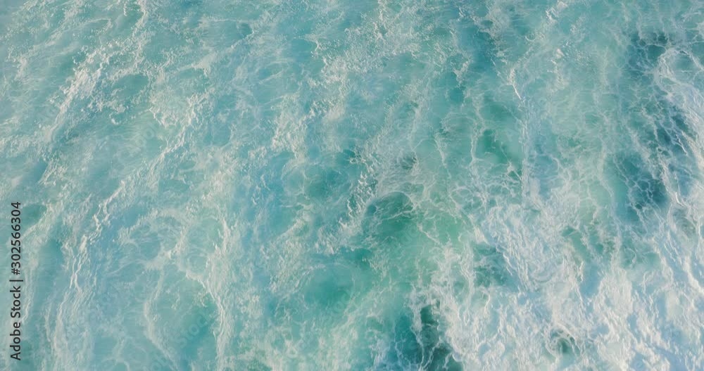 Aerial top down view flying over a breaking wave with ocean white water in motion and foam textures, ocean texture background