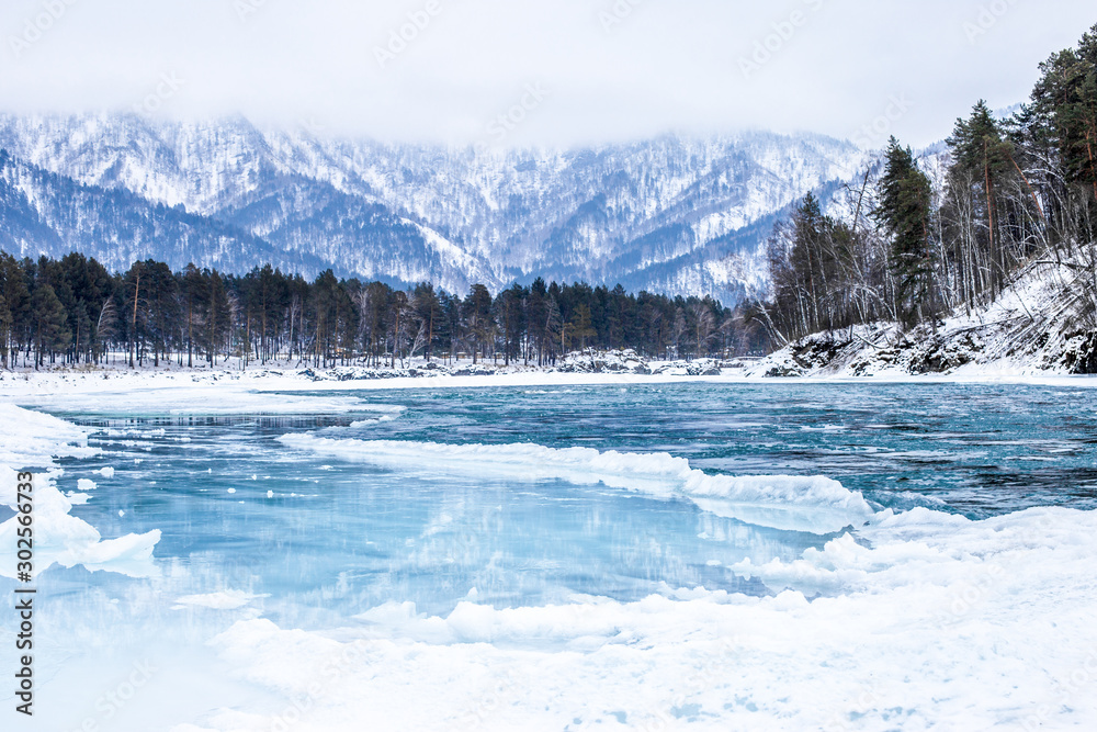 The blue ice of the mountain river Katun in the winter. Landscape with river and mountains in Altai. Siberia. Altai. Russia.