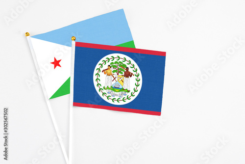 Belize and Djibouti stick flags on white background. High quality fabric, miniature national flag. Peaceful global concept.White floor for copy space.