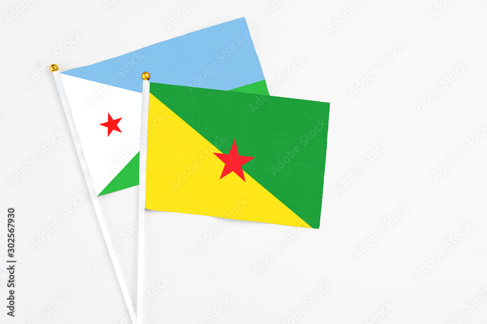 French Guiana and Djibouti stick flags on white background. High quality fabric, miniature national flag. Peaceful global concept.White floor for copy space. French Guiana and Djibouti stick flags on white background. High quality fabric, miniature national flag. Peaceful global concept.White floor for copy space.