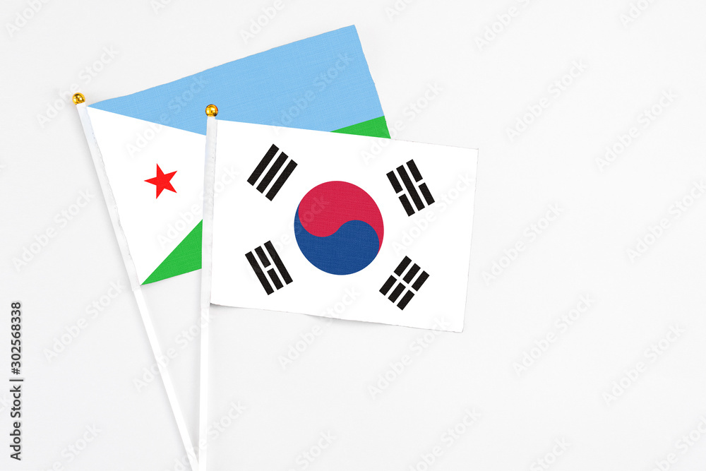 South Korea and Djibouti stick flags on white background. High quality fabric, miniature national flag. Peaceful global concept.White floor for copy space.