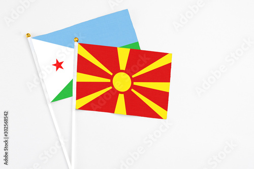 Macedonia and Djibouti stick flags on white background. High quality fabric, miniature national flag. Peaceful global concept.White floor for copy space.