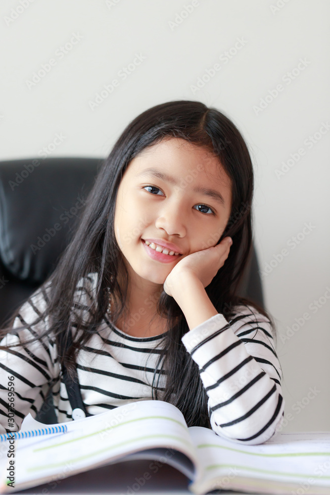 Portrait little Asian girl sitting chin and doing homework for self learning and education concept select focus shallow depth of field Portrait little Asian girl sitting chin and doing homework for self learning and education concept select focus shallow depth of field
