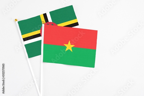 Burkina Faso and Dominica stick flags on white background. High quality fabric, miniature national flag. Peaceful global concept.White floor for copy space.