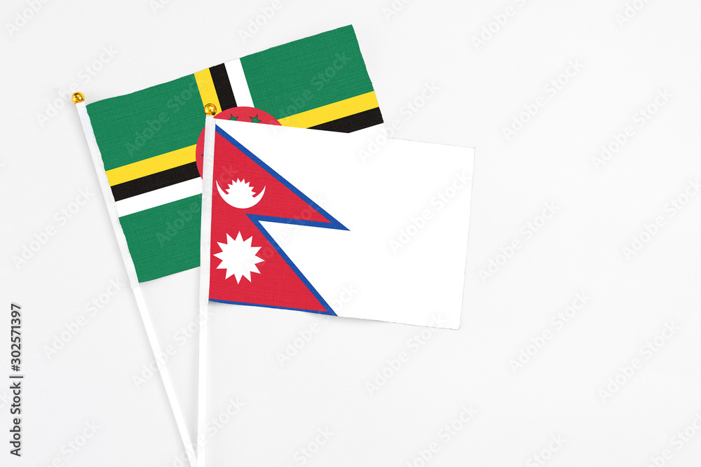 Nepal and Dominica stick flags on white background. High quality fabric, miniature national flag. Peaceful global concept.White floor for copy space. Nepal and Dominica stick flags on white background. High quality fabric, miniature national flag. Peaceful global concept.White floor for copy space.