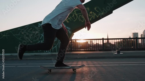 skateboarder pushing on bridge in super slow motion in front frankfurt skyline skyscrapers sunset