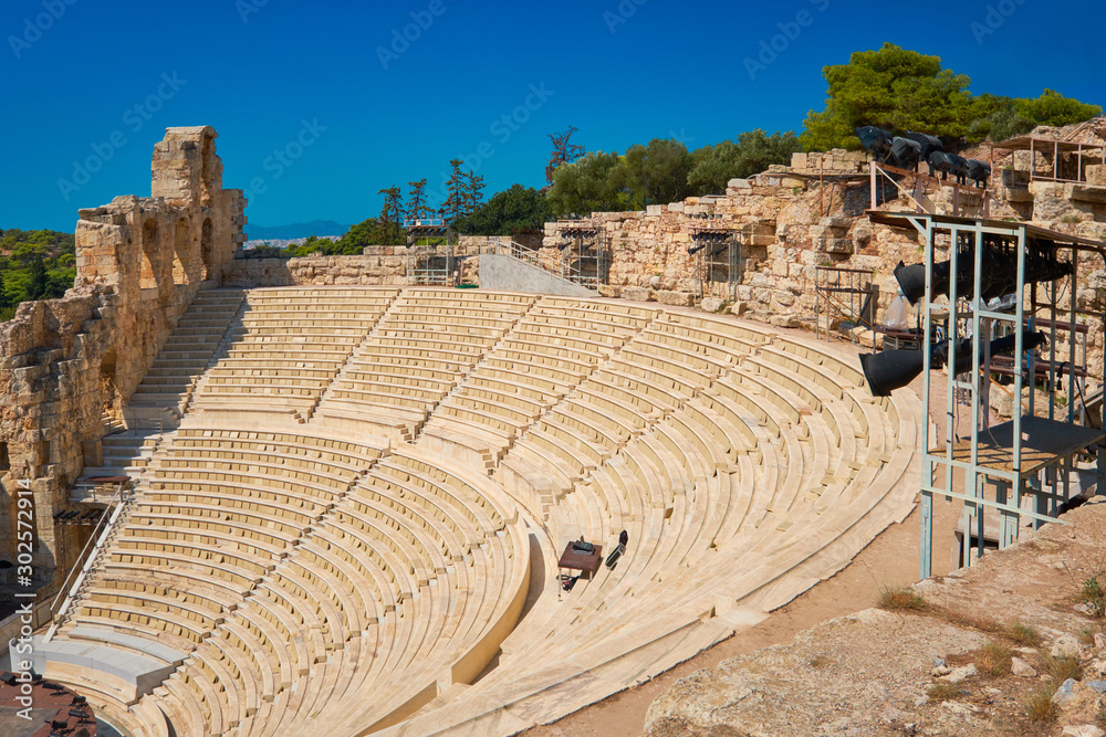 Panoramic image of ancient Greek theatre under Acropolis hill in Athens, Greece. Empty amphitheater with blue sky.