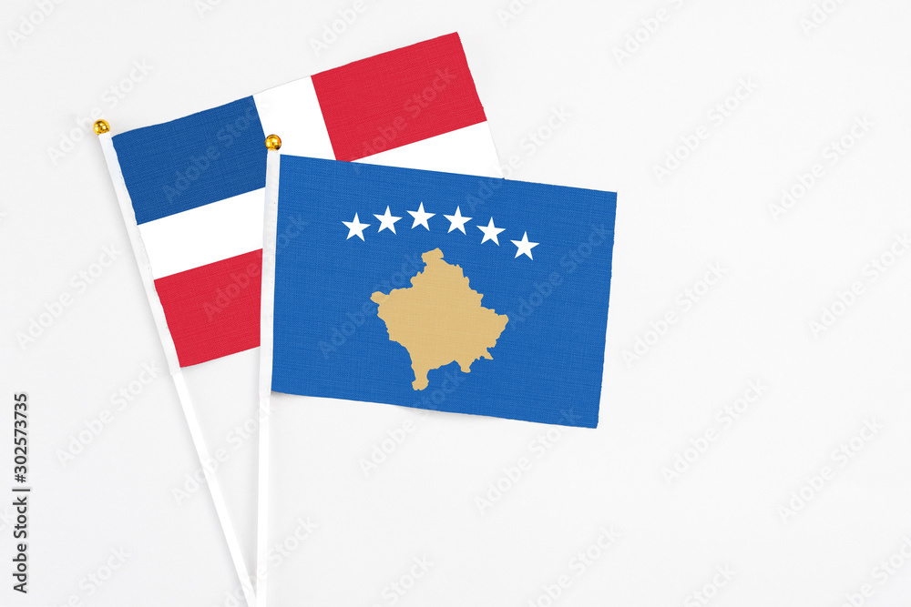 Kosovo and Dominican Republic stick flags on white background. High quality fabric, miniature national flag. Peaceful global concept.White floor for copy space. Kosovo and Dominican Republic stick flags on white background. High quality fabric, miniature national flag. Peaceful global concept.White floor for copy space.