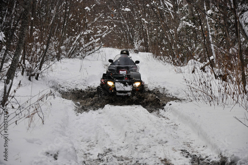 An ATV on wheels ride on a taiga forest road in winter
