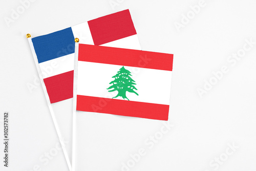 Lebanon and Dominican Republic stick flags on white background. High quality fabric, miniature national flag. Peaceful global concept.White floor for copy space. photo