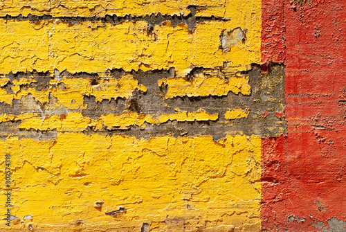 Yellow and Red Paint Peeling Off of Concrete Wall