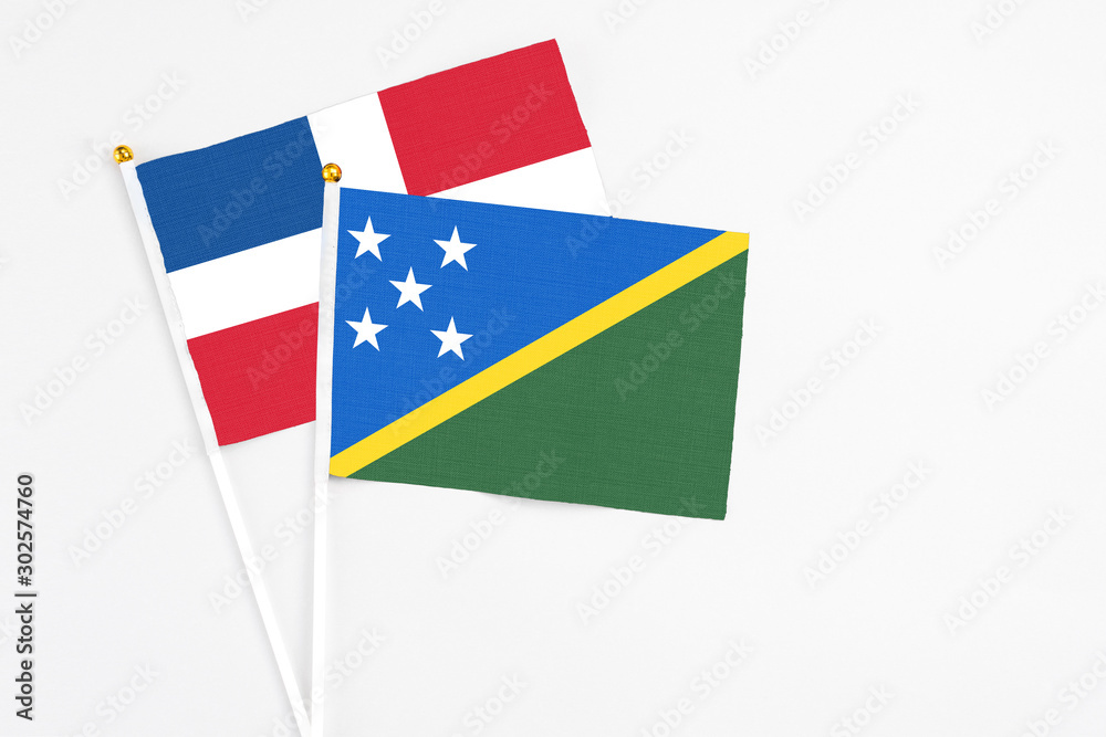 Solomon Islands and Dominican Republic stick flags on white background. High quality fabric, miniature national flag. Peaceful global concept.White floor for copy space.