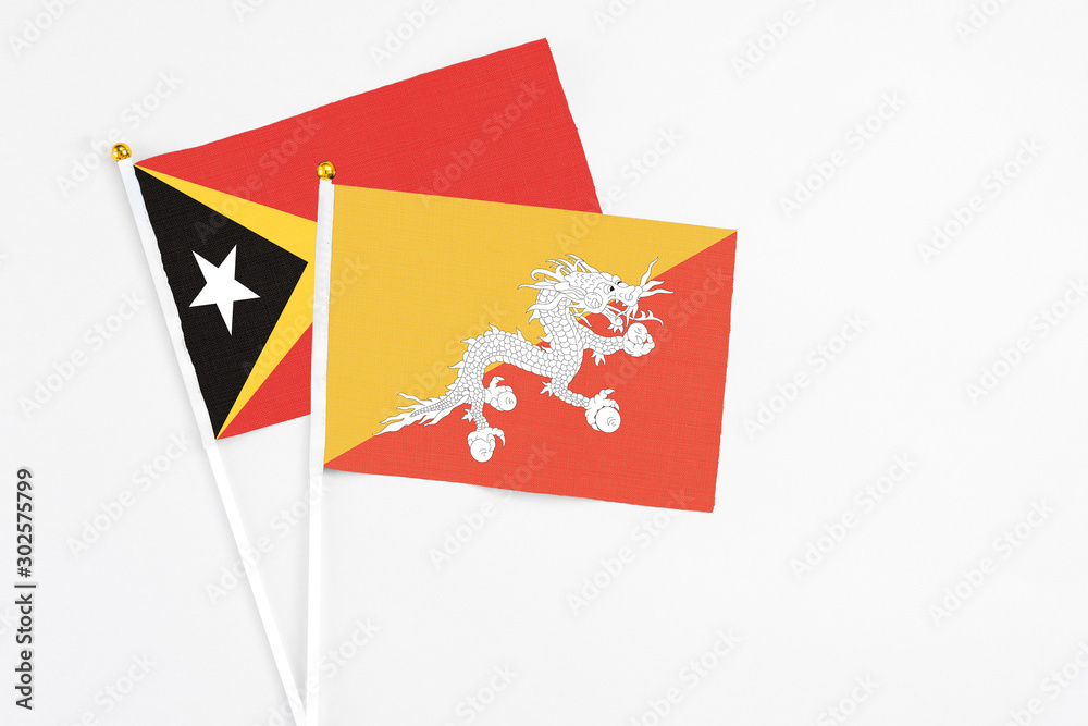 Bhutan and East Timor stick flags on white background. High quality fabric, miniature national flag. Peaceful global concept.White floor for copy space. Bhutan and East Timor stick flags on white background. High quality fabric, miniature national flag. Peaceful global concept.White floor for copy space.
