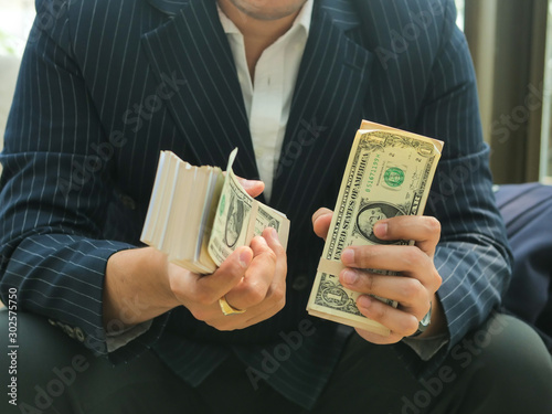 Rich businessman in real estate concept counting money in office.