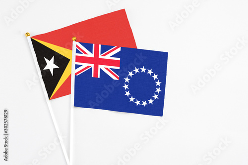 Cook Islands and East Timor stick flags on white background. High quality fabric, miniature national flag. Peaceful global concept.White floor for copy space.